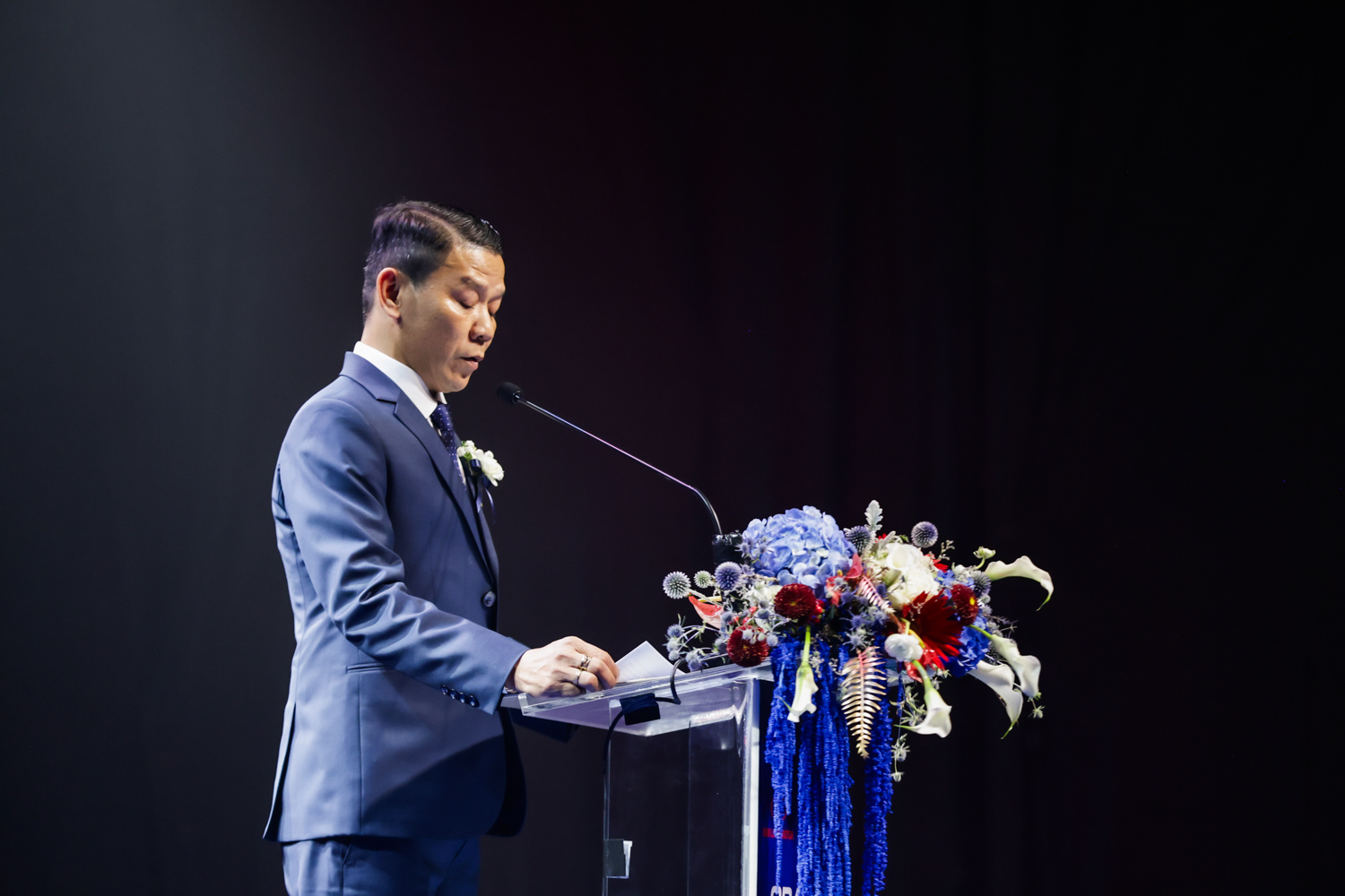 ผู้บริหารกล่าวบนโพเดียมประดับดอกไม้ในงานเปิดตัวรถ KIM LONG MOTOR GRAND LAUNCH 2026